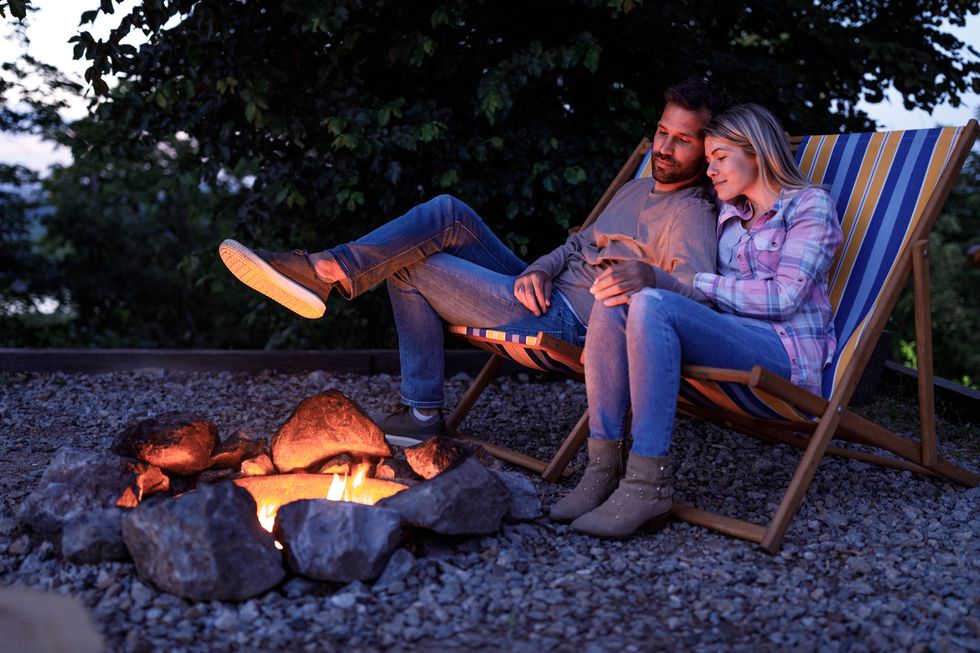 young loving couple relaxing in deck chairs by the bonfire