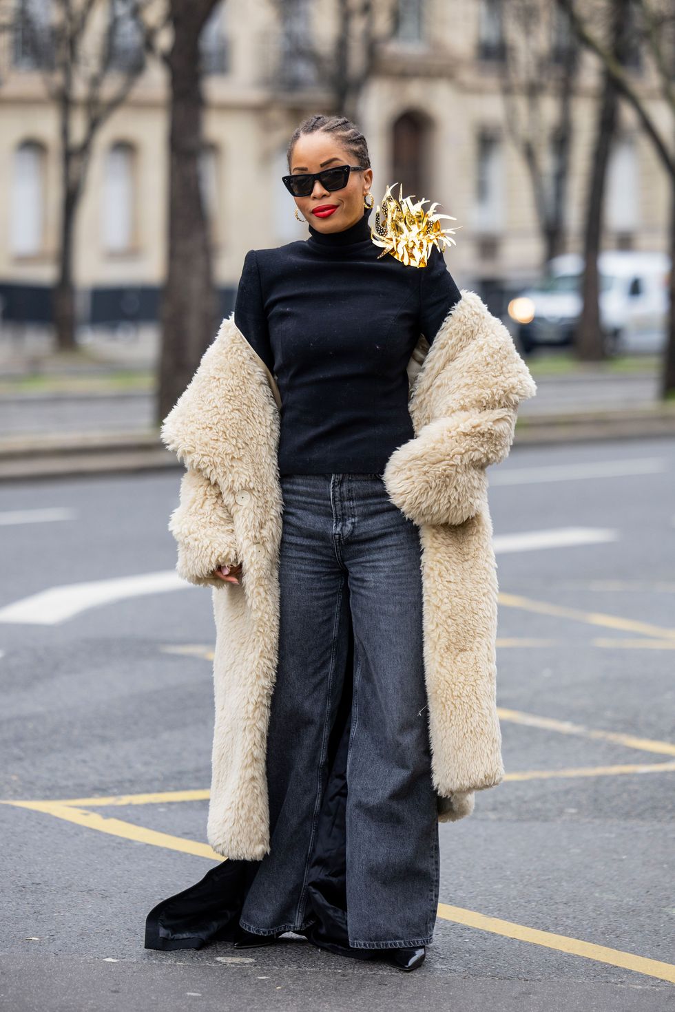 a woman in a fur coat and sunglasses standing in a street