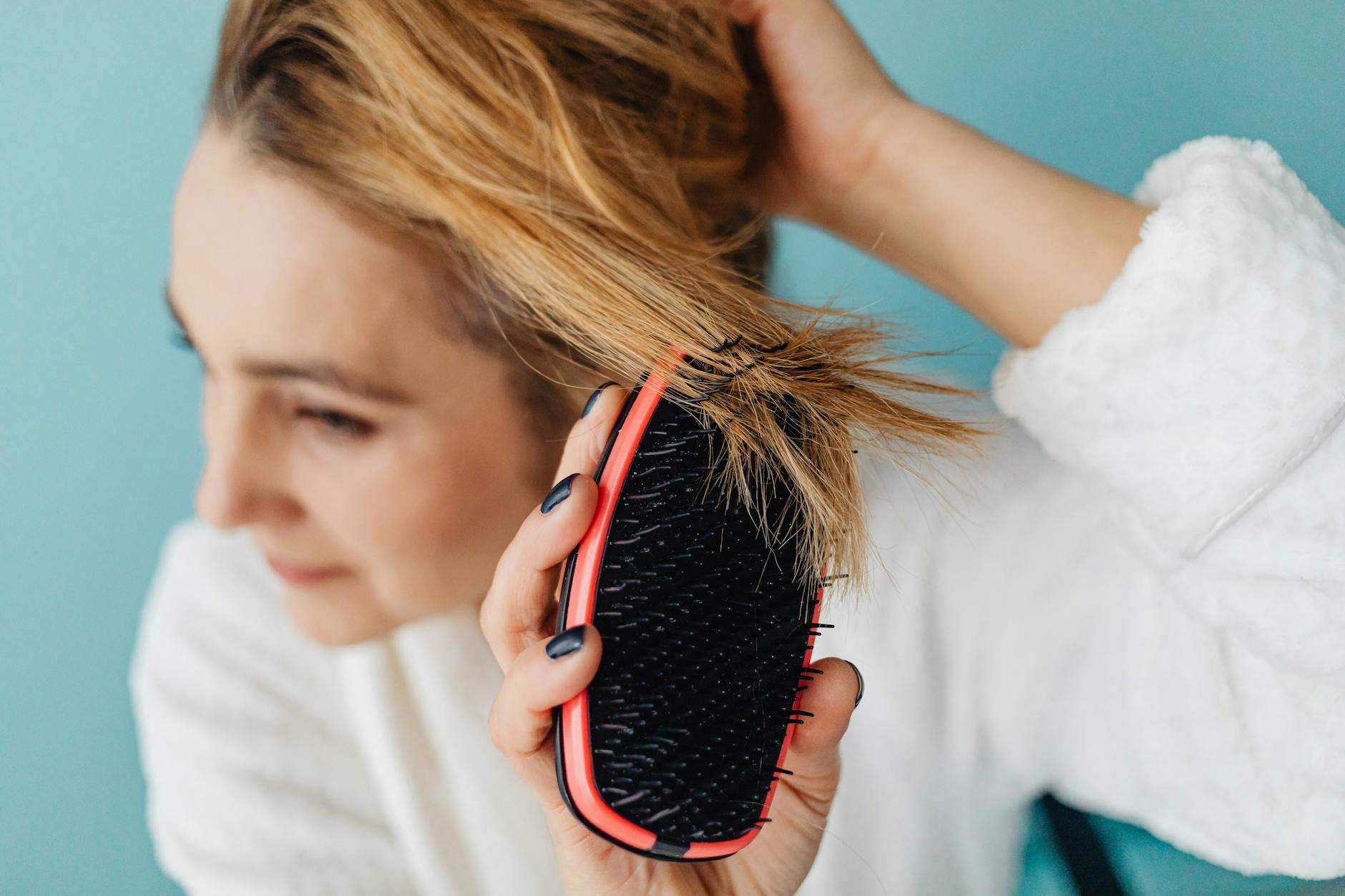 Close-up of a wooden scalp massage brush being used on hair