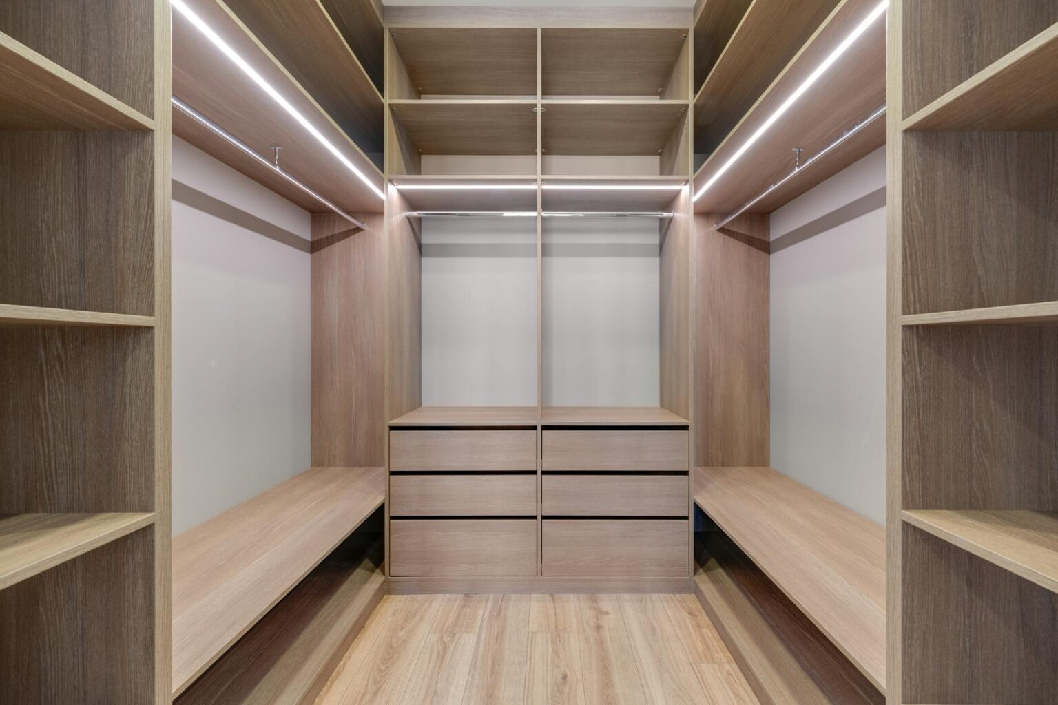 Professional organizer arranging clothes in a minimalist walk-in closet with efficient storage solutions