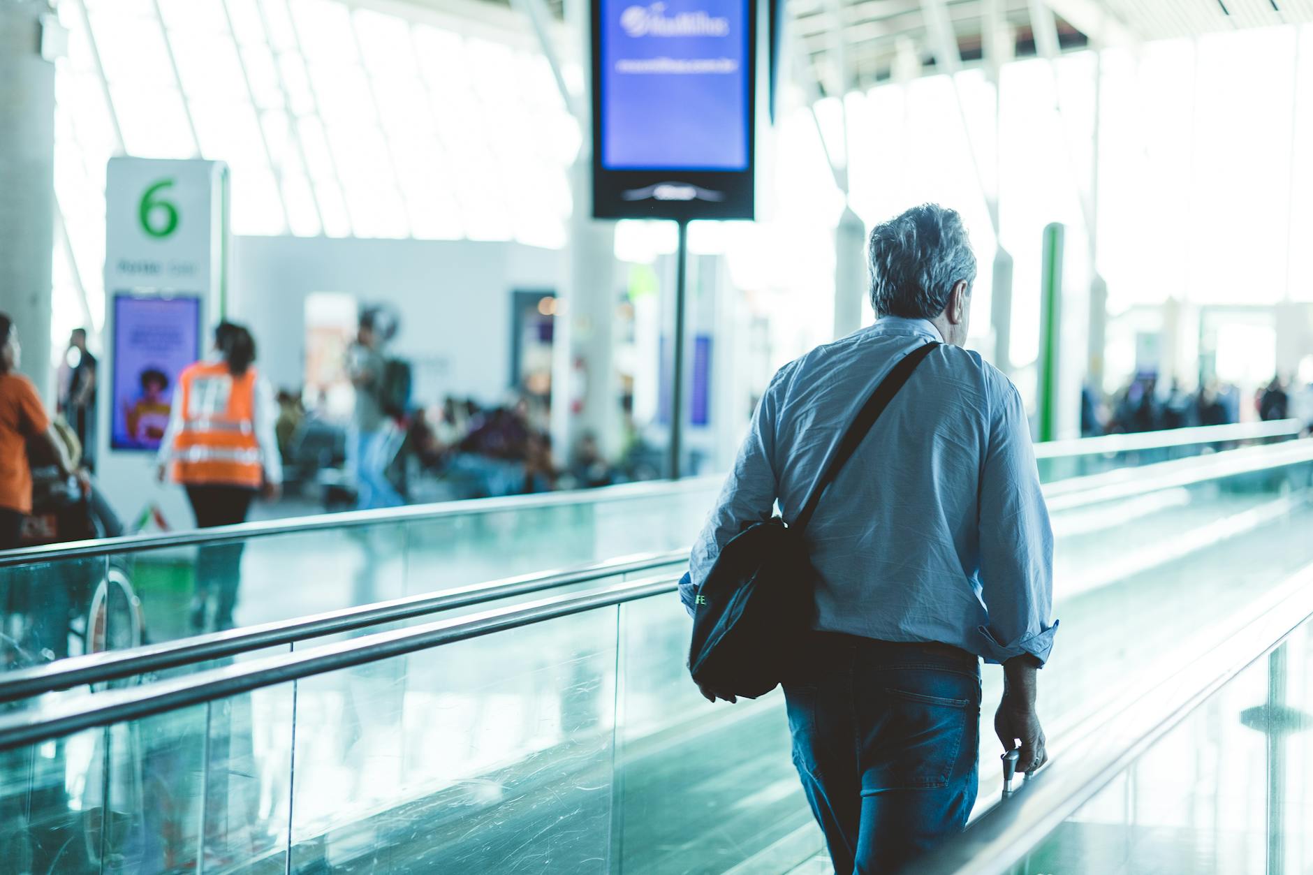 Modern airport terminal with departure gates and travelers walking through the concourse
