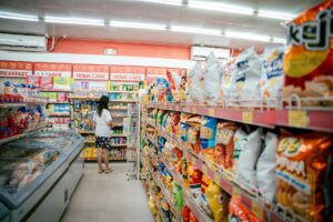Bright grocery store aisle with fluorescent lighting and product displays creating potential runway space