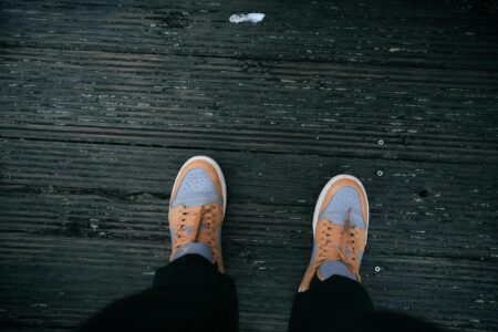 Close-up of ballet pointe shoes and athletic sneakers side by side, showing the contrast between traditional and modern dance footwear