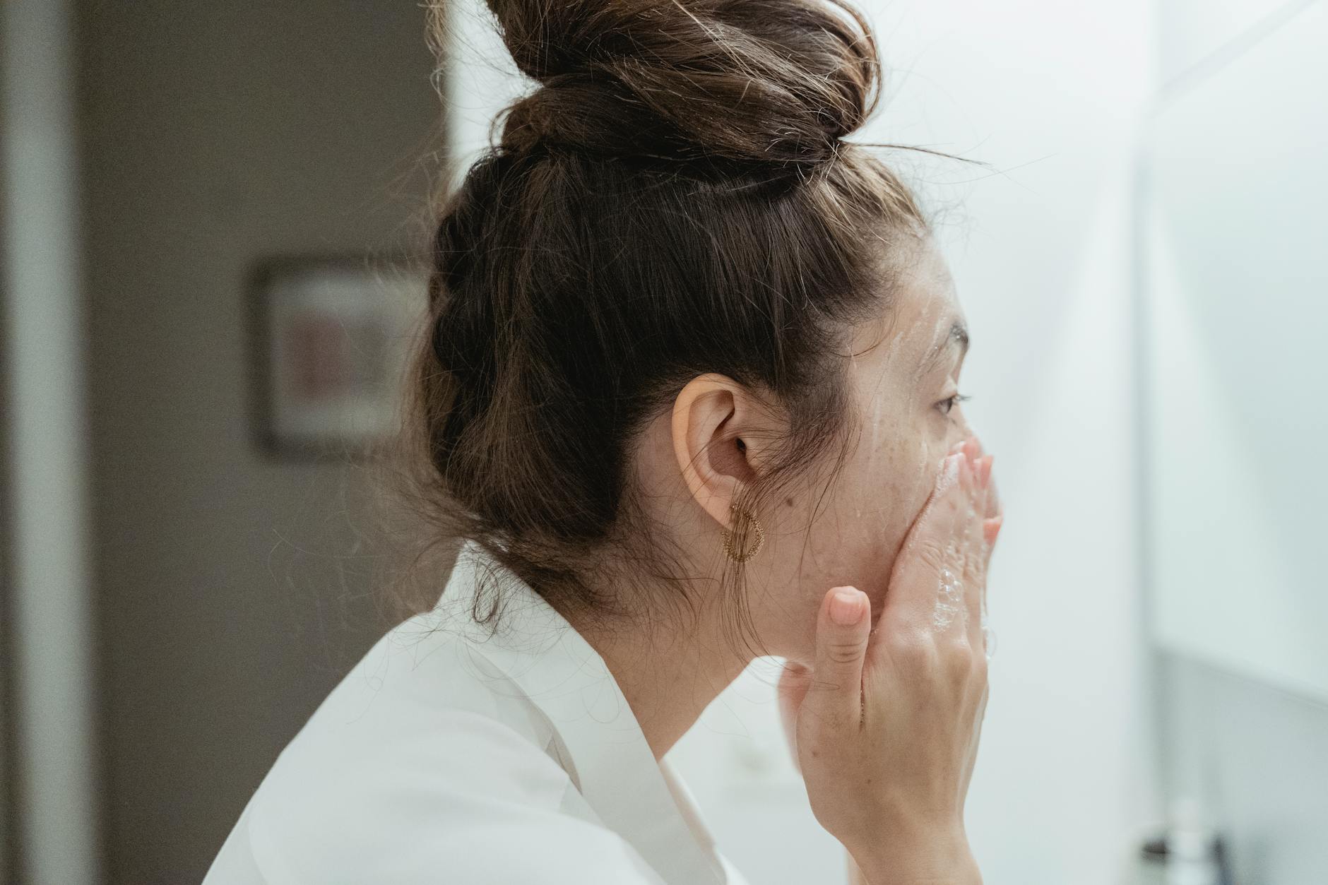 Woman applying skincare treatment looking in mirror