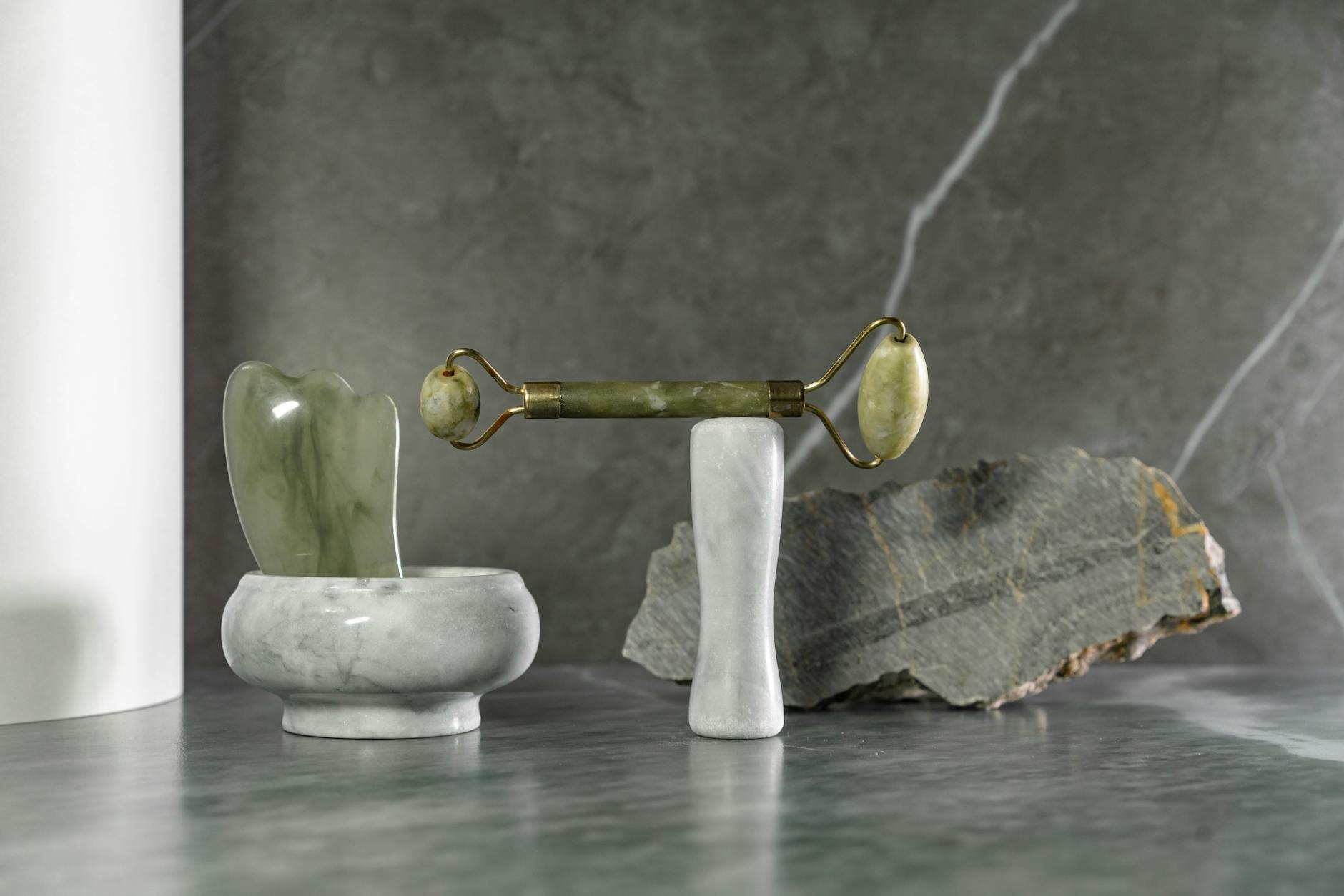 Collection of natural stone facial massage tools including jade rollers and gua sha implements