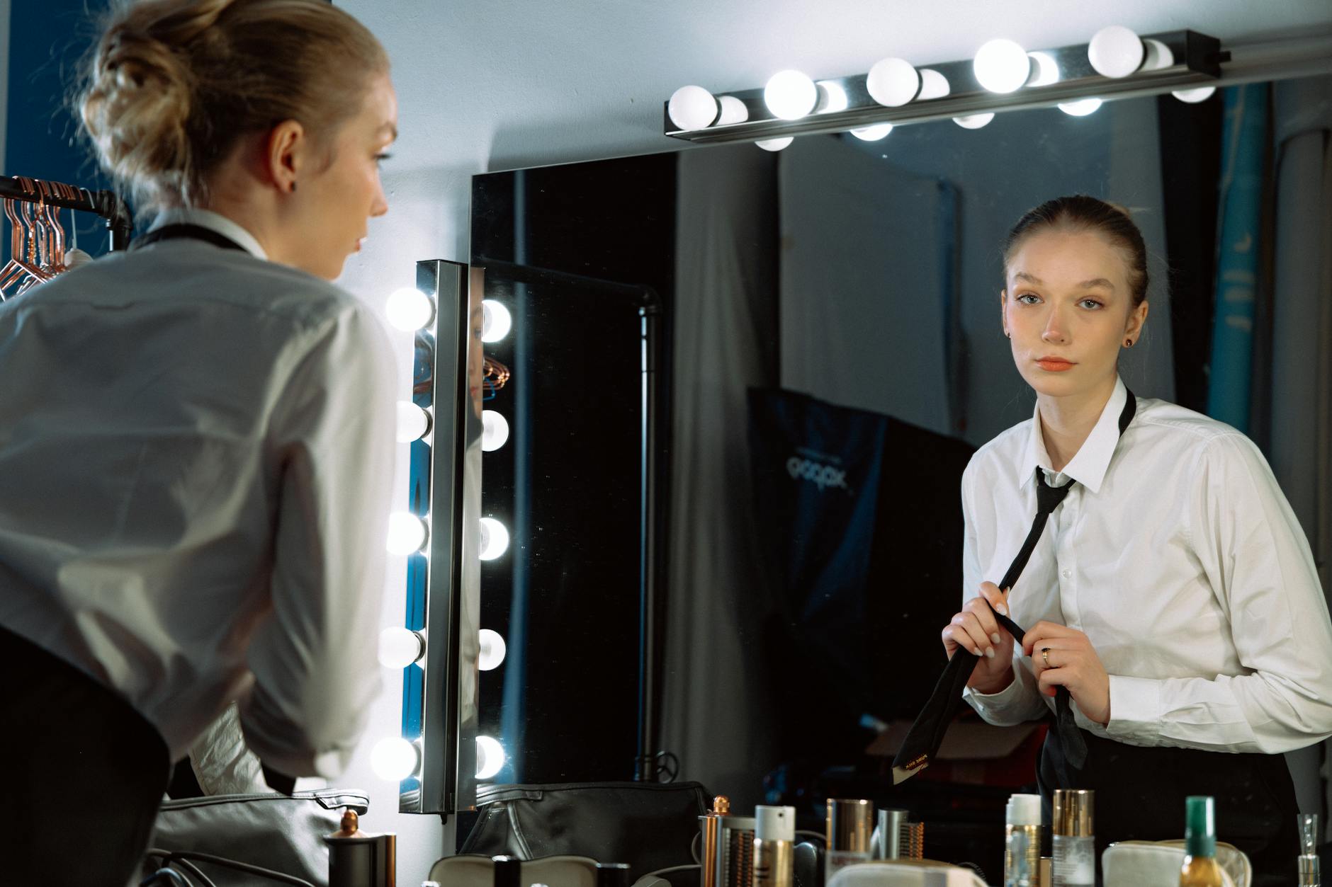 Behind-the-scenes view of fashion show preparation with clothing racks and styling equipment in an industrial setting