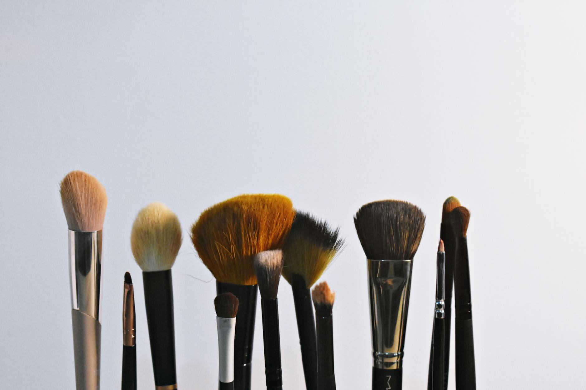 Professional makeup brushes and eyeliner tools arranged on white surface