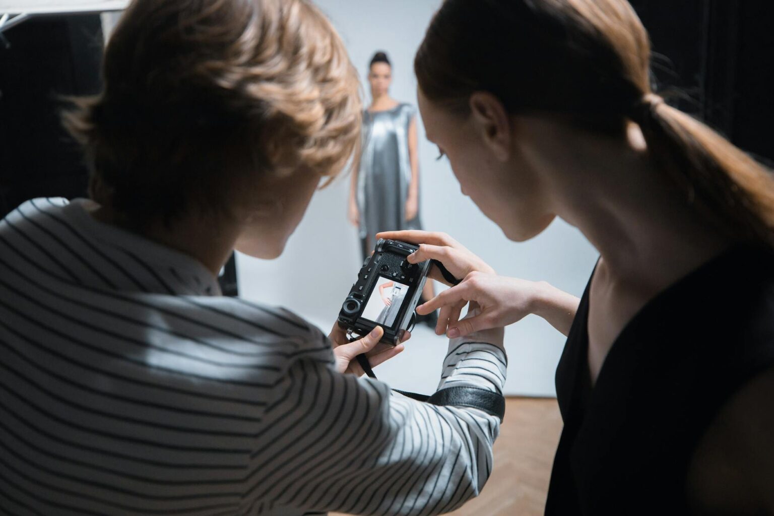 Professional fashion photographer taking pictures of model during outdoor winter photoshoot