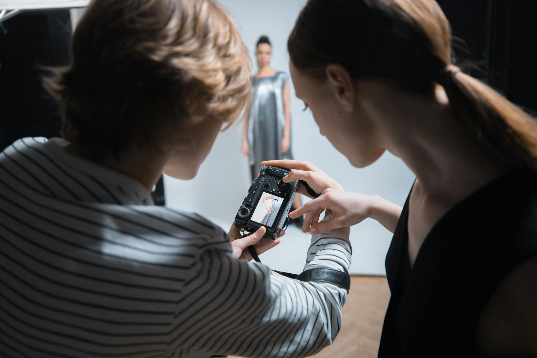 Professional fashion photographer taking pictures of model during outdoor winter photoshoot