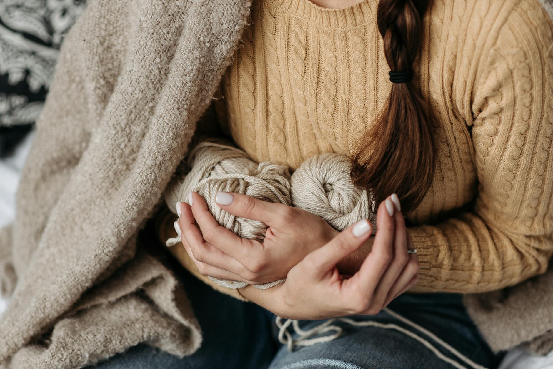 Close-up of hands working on knitted fabric, illustrating the handmade artisanal process behind crochet garments