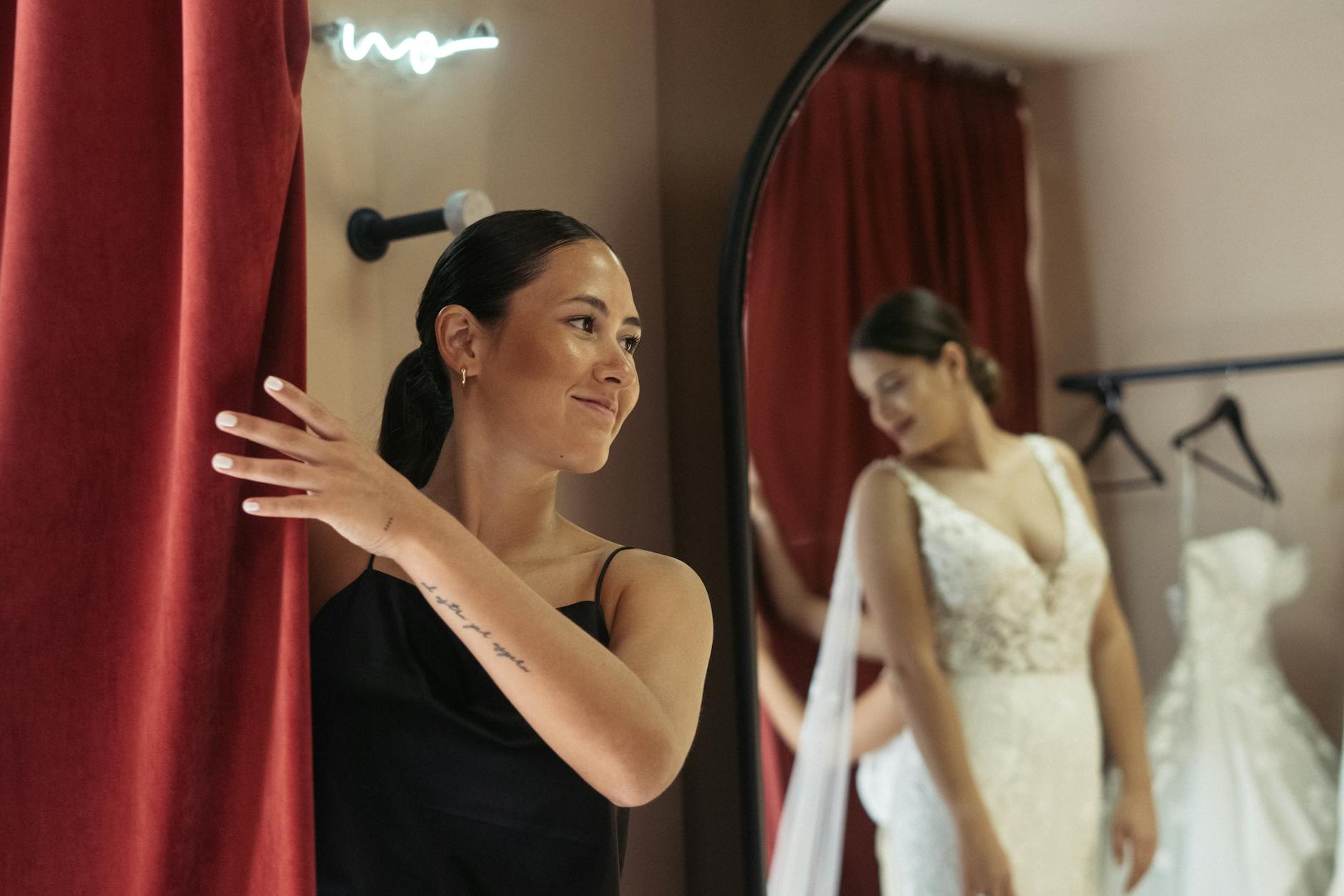 Bride trying on wedding dress while looking in mirror during fitting