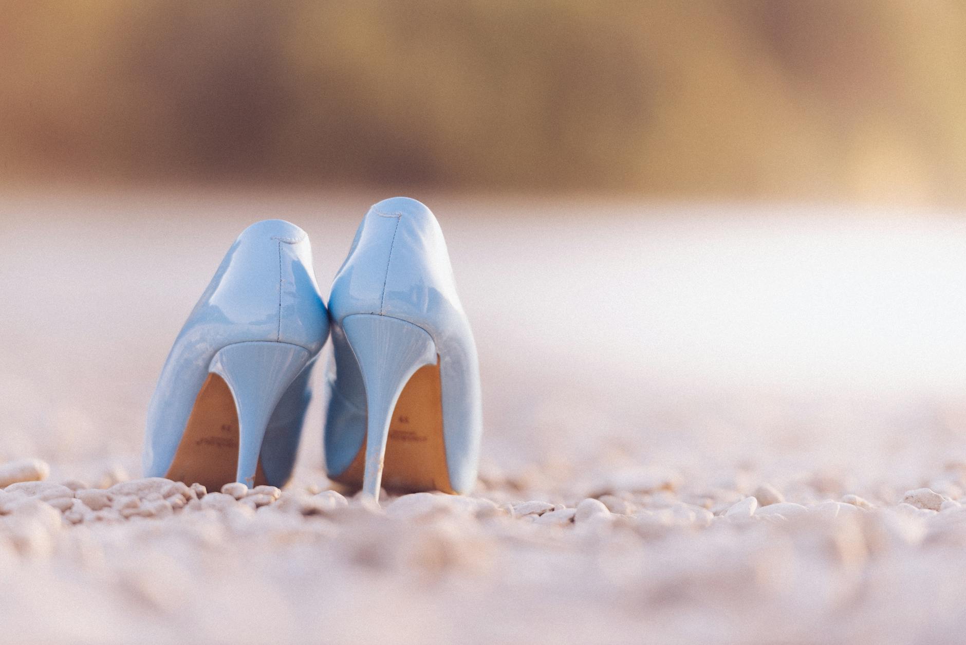 Close-up of a luxury high heel shoe with a red sole on a reflective surface