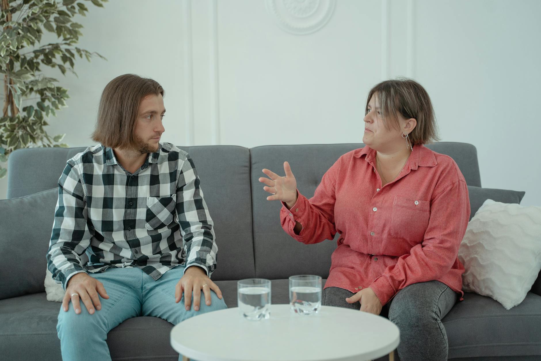 Two people sitting on a couch having a serious conversation