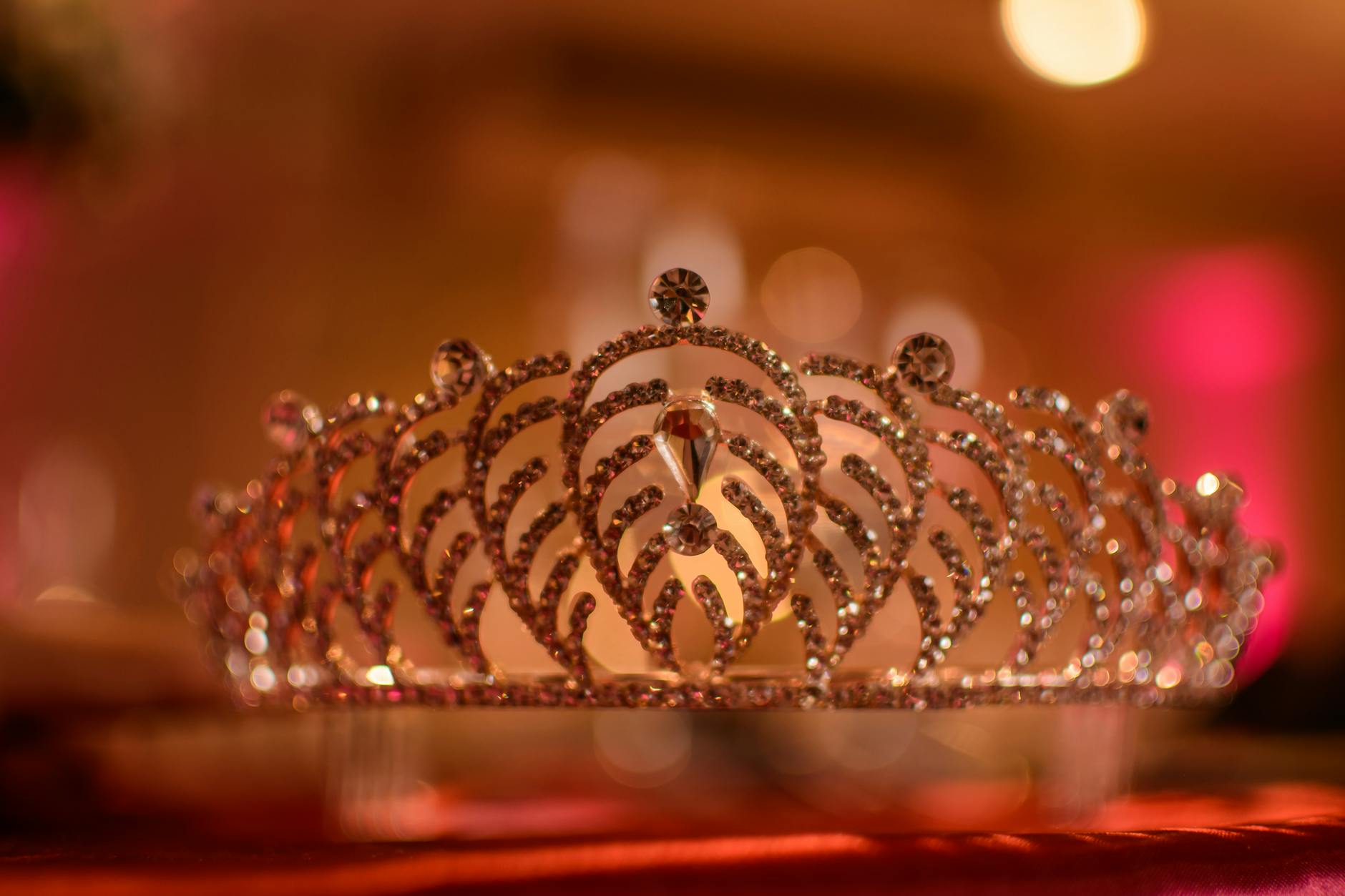 Ornate golden crown with precious gems on velvet cushion