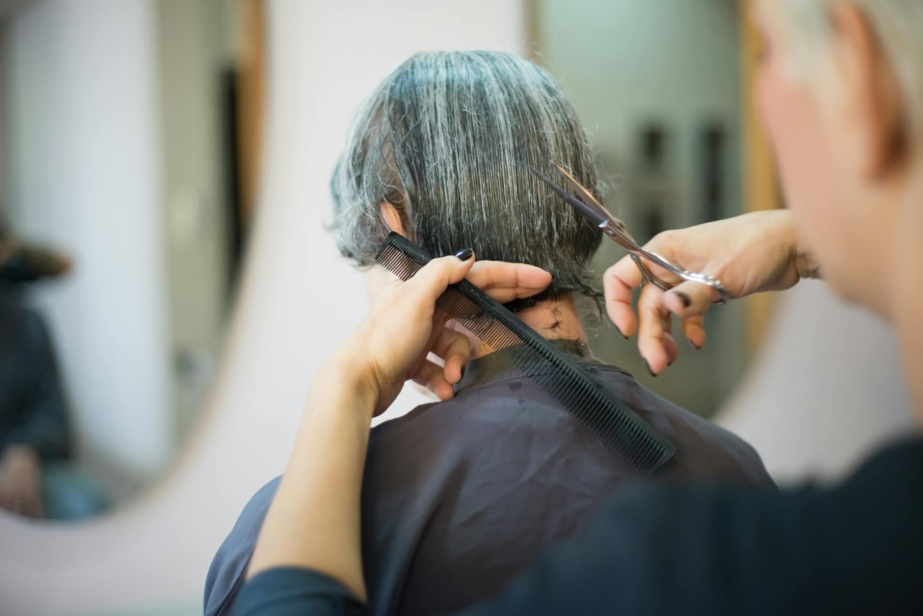 Professional hairstylist cutting hair with precision scissors in salon