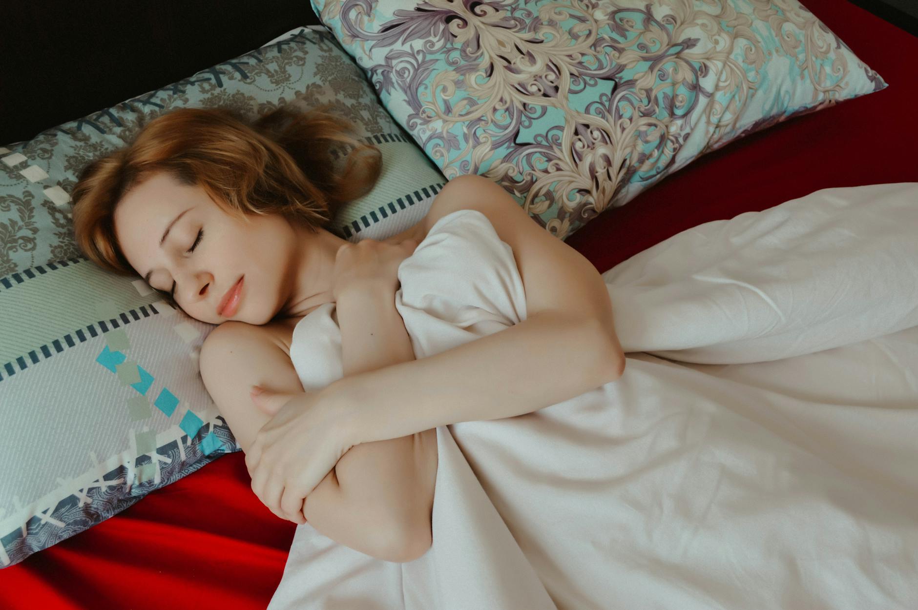 Woman with straight black hair lying on silk pillowcase demonstrating protective sleep method