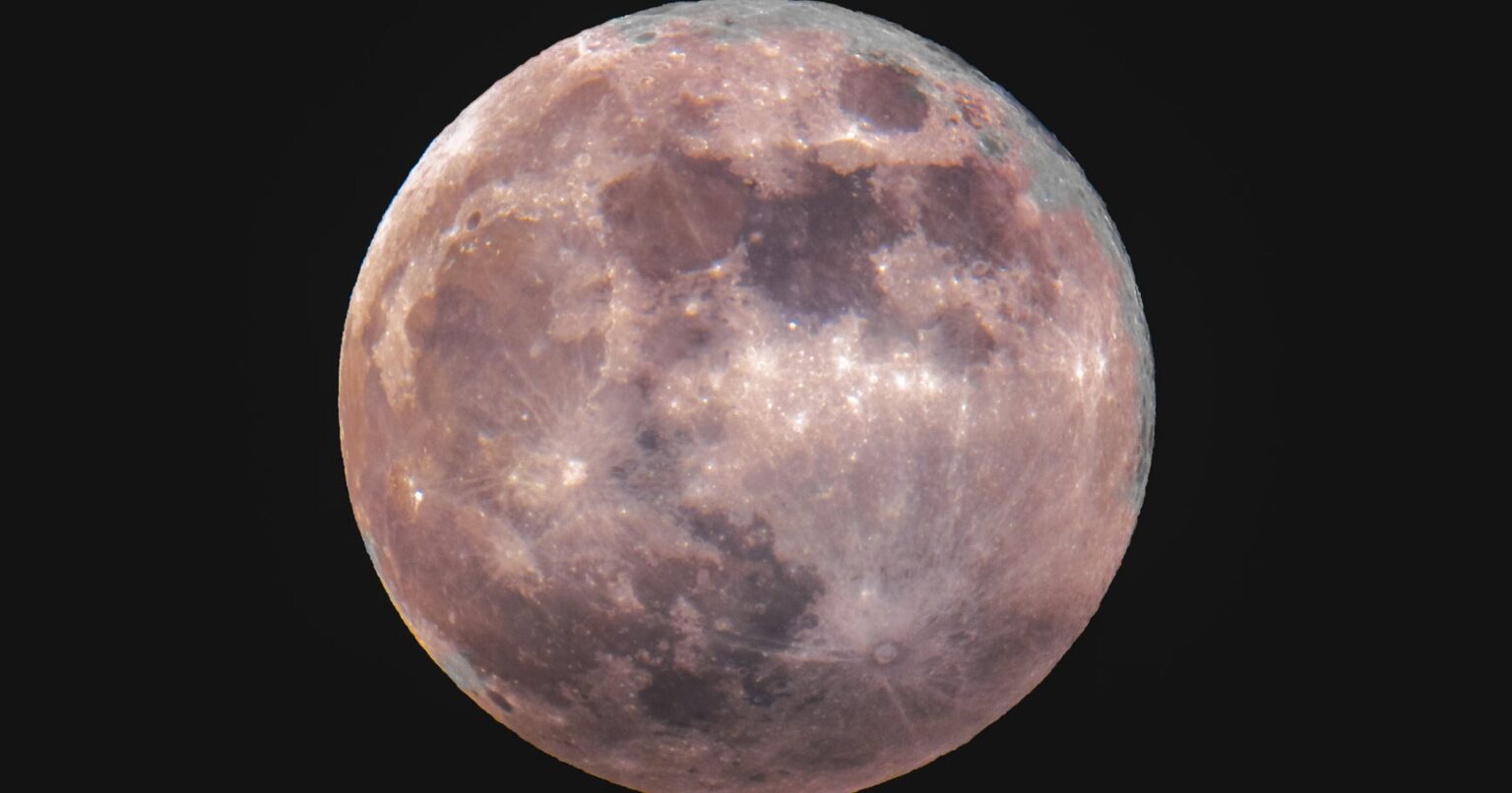 The Strawberry Full Moon In Capricorn Is Here — & You Need To Take A Leap Large full moon glowing against a dark blue summer night sky