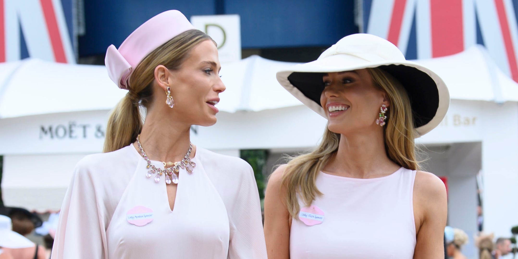 Two women in matching baby pink formal dresses at an outdoor event