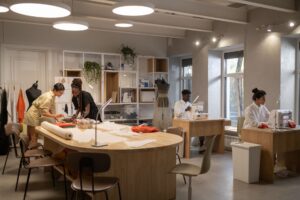 Chanel Ends Product Destruction, Routes Unsold Goods Through New Circular Units Interior of a high-end fashion atelier with fabric materials and workbenches