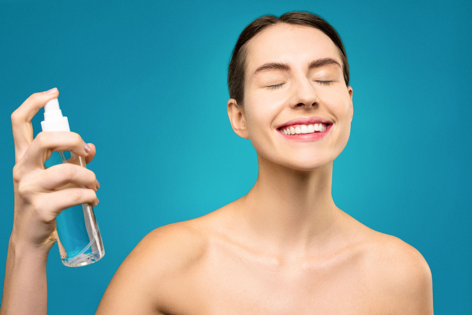 Woman applying body mist spray to her neck in warm sunlight