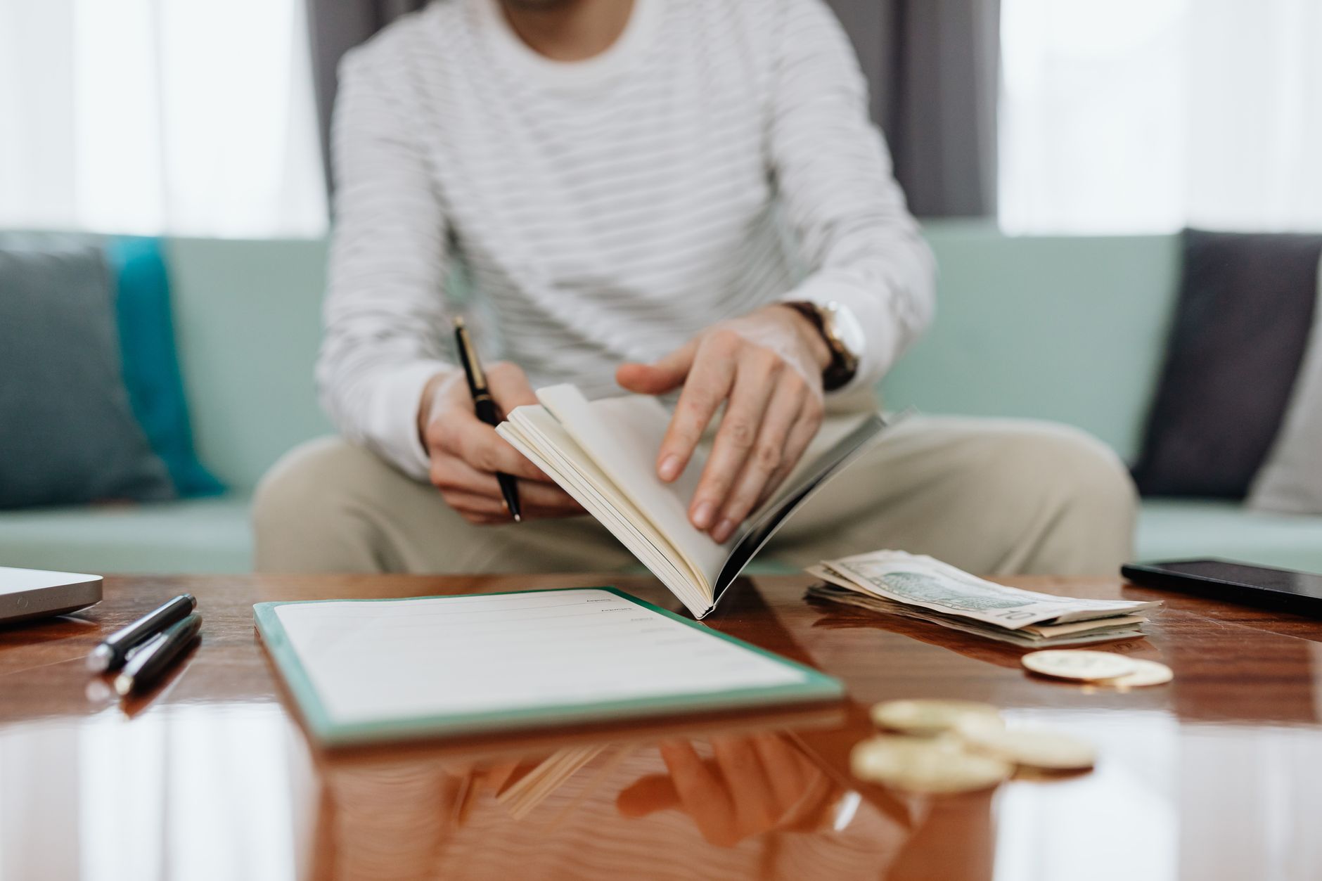Open notebook and pen beside a glass of white wine on a wooden table