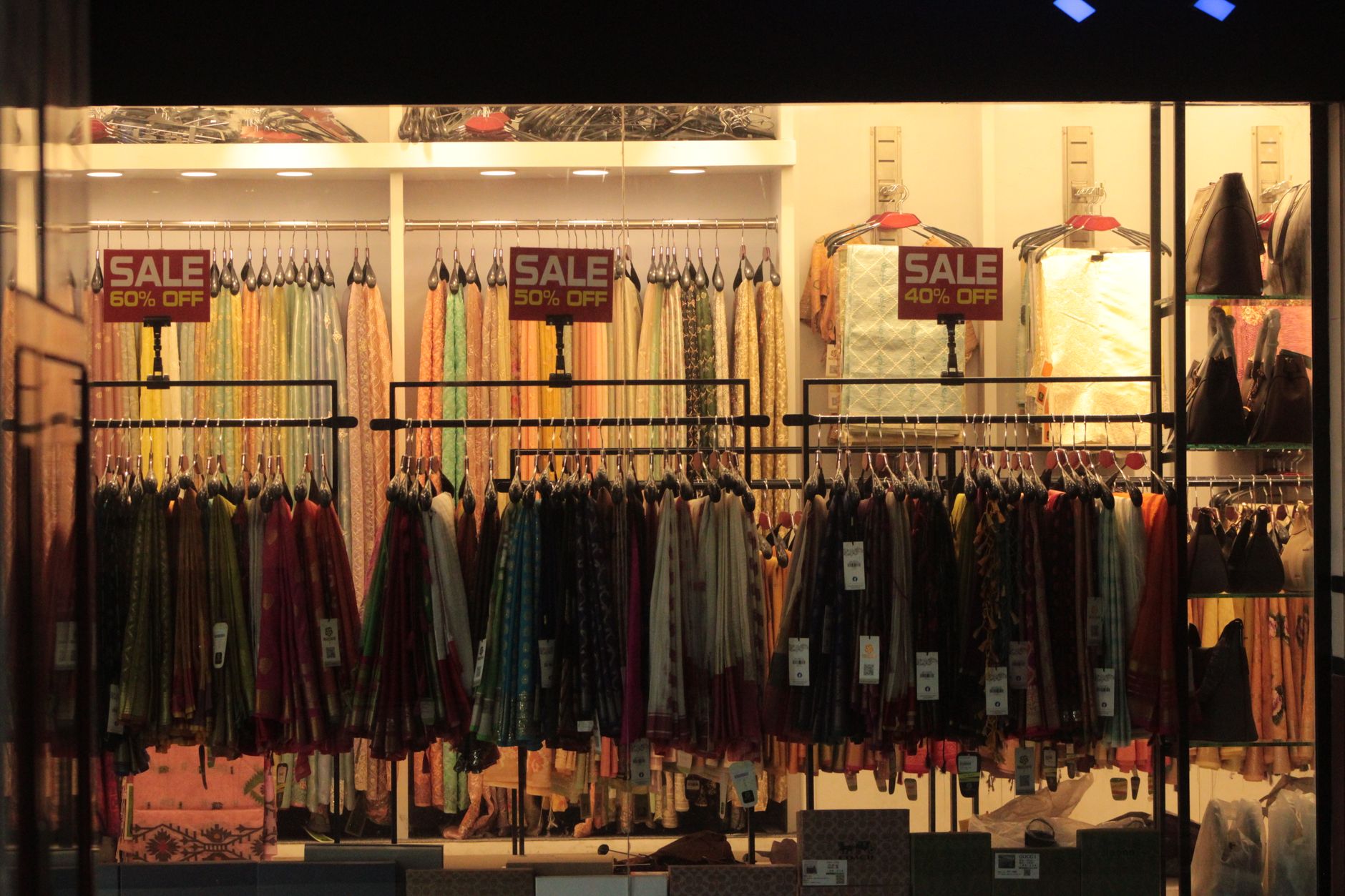 Shopper browsing discounted clothing on a store rack during a seasonal sale