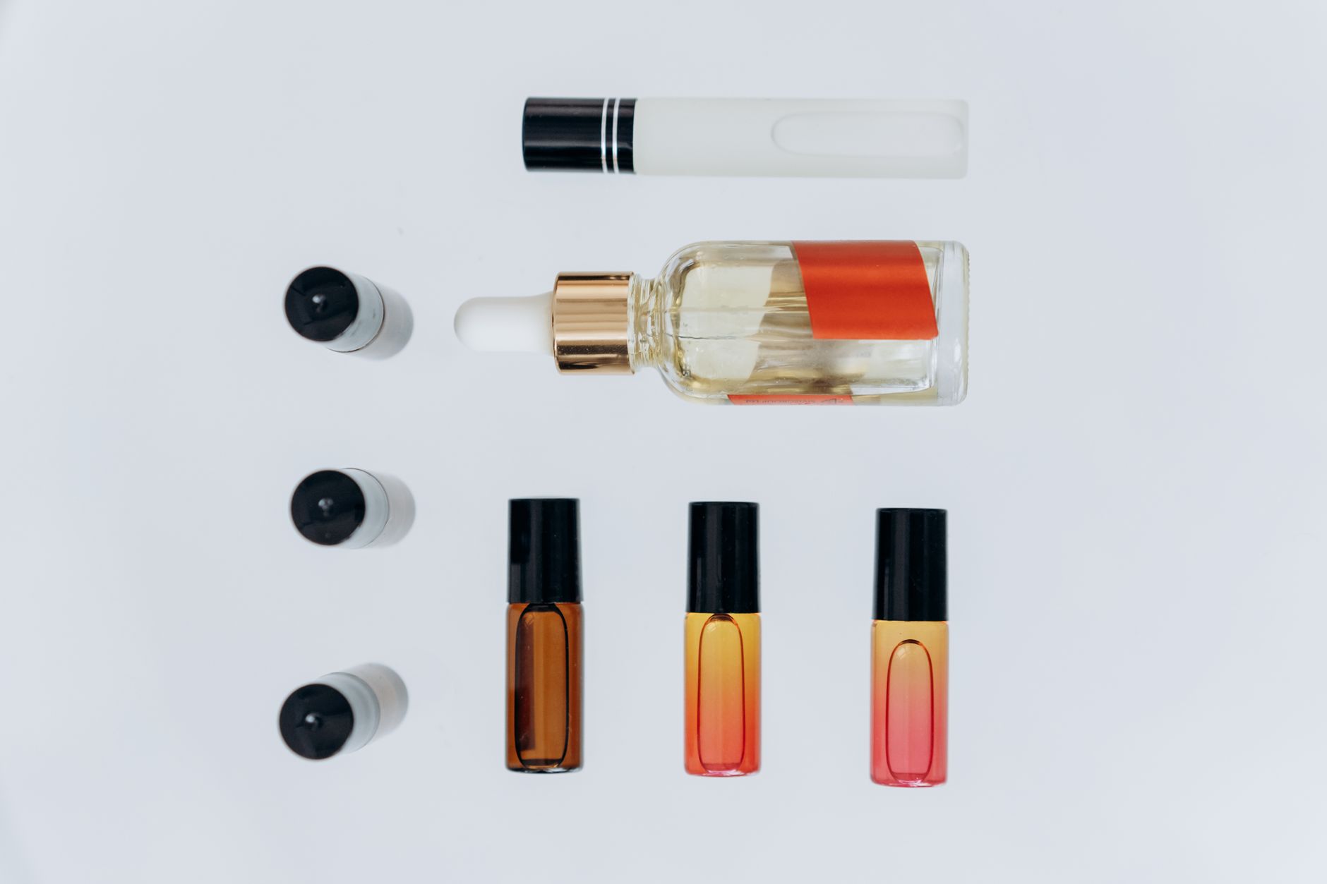 Flat lay of multiple fragrance bottles on white background with tropical leaves
