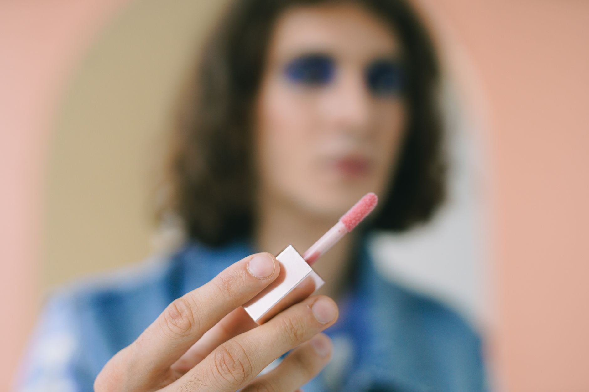 Pink lip gloss and beauty products arranged on a vanity surface