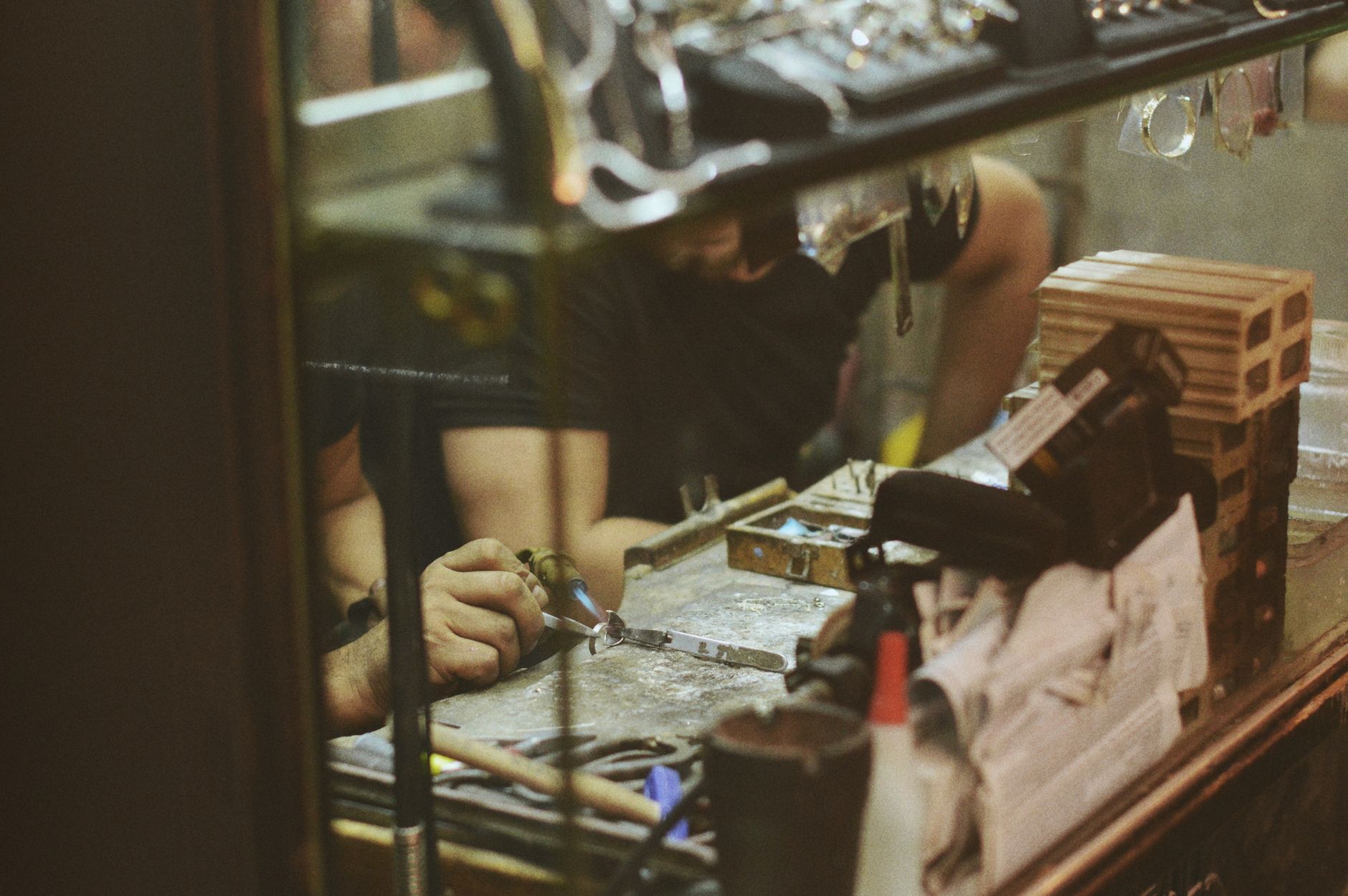 Craftsperson working on detailed enameled metalwork by hand
