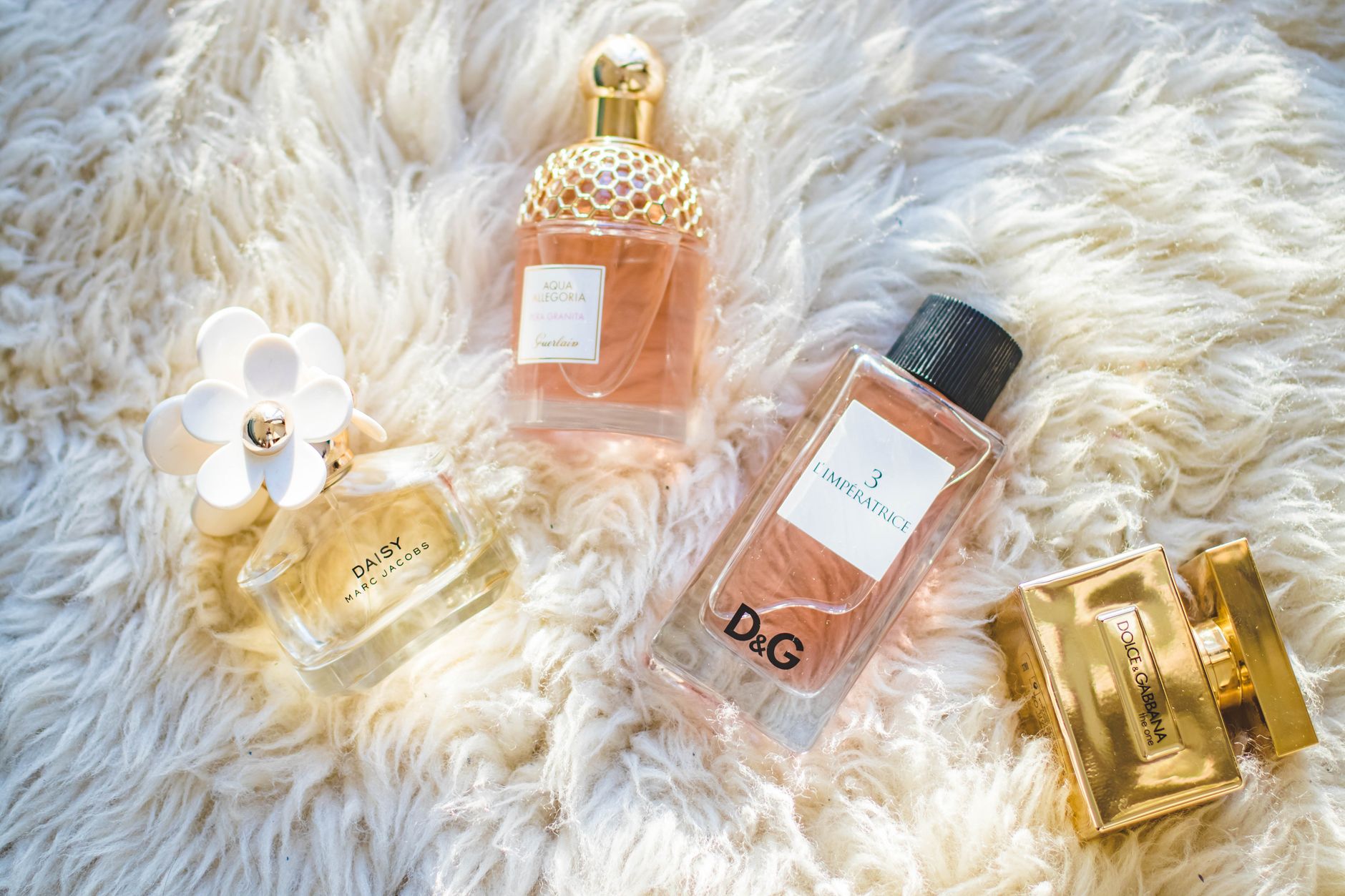 Several glass perfume bottles arranged on a soft surface in warm light