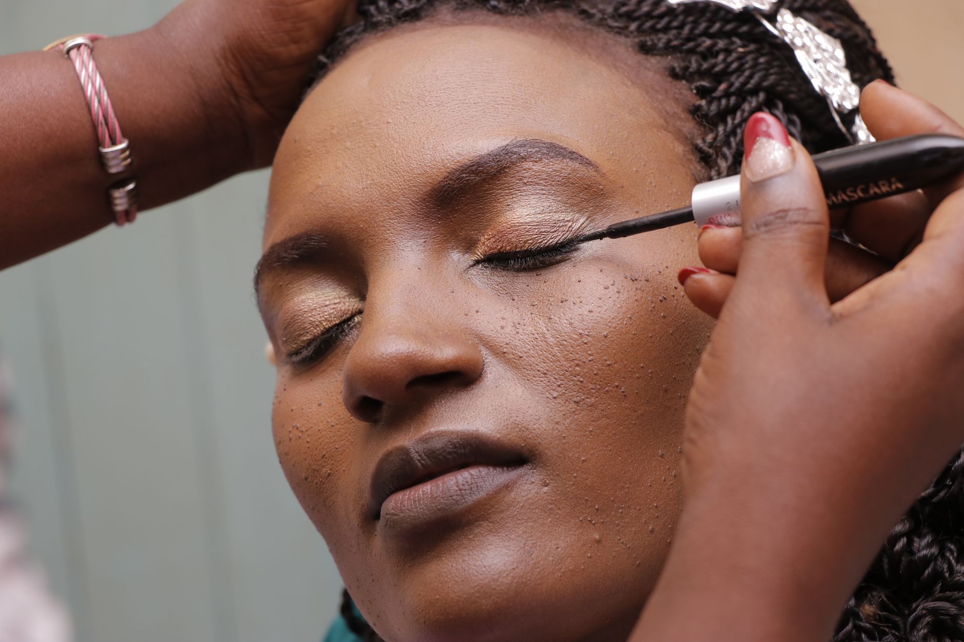 Woman applying mascara to defined lashes with careful brush strokes