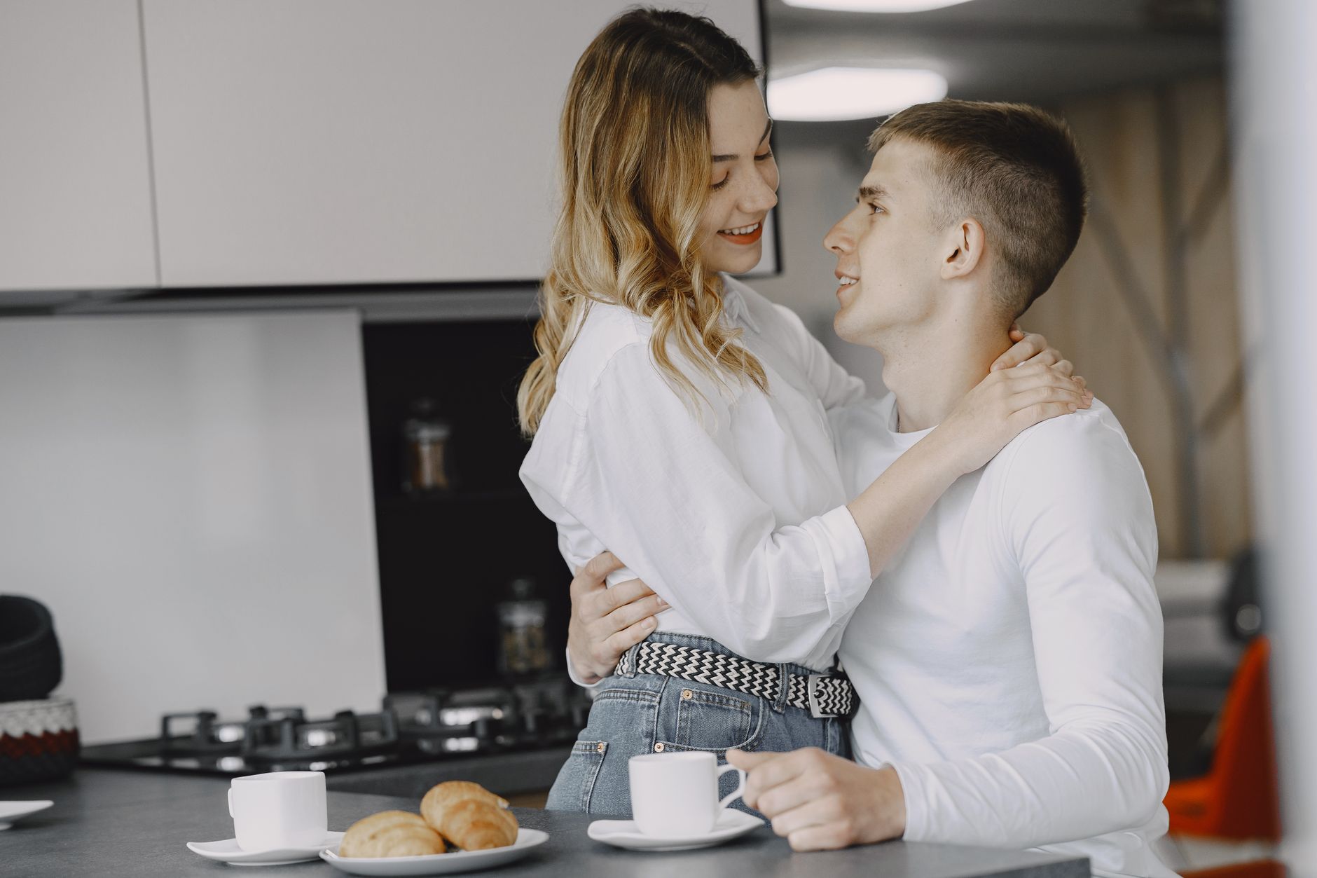Young couple reviewing finances together at a kitchen table with coffee cups nearby