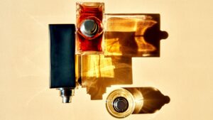 Fall 2026 Fragrances Abandon Sweetness for Spice and Smoke Dark amber glass perfume bottle on a moody textured surface evoking fall fragrance
