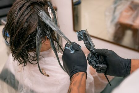 Behind Lili Reinhart’s Striking Hair Transformation for The Love Hypothesis Stylist applying hair color treatment in a professional salon setting