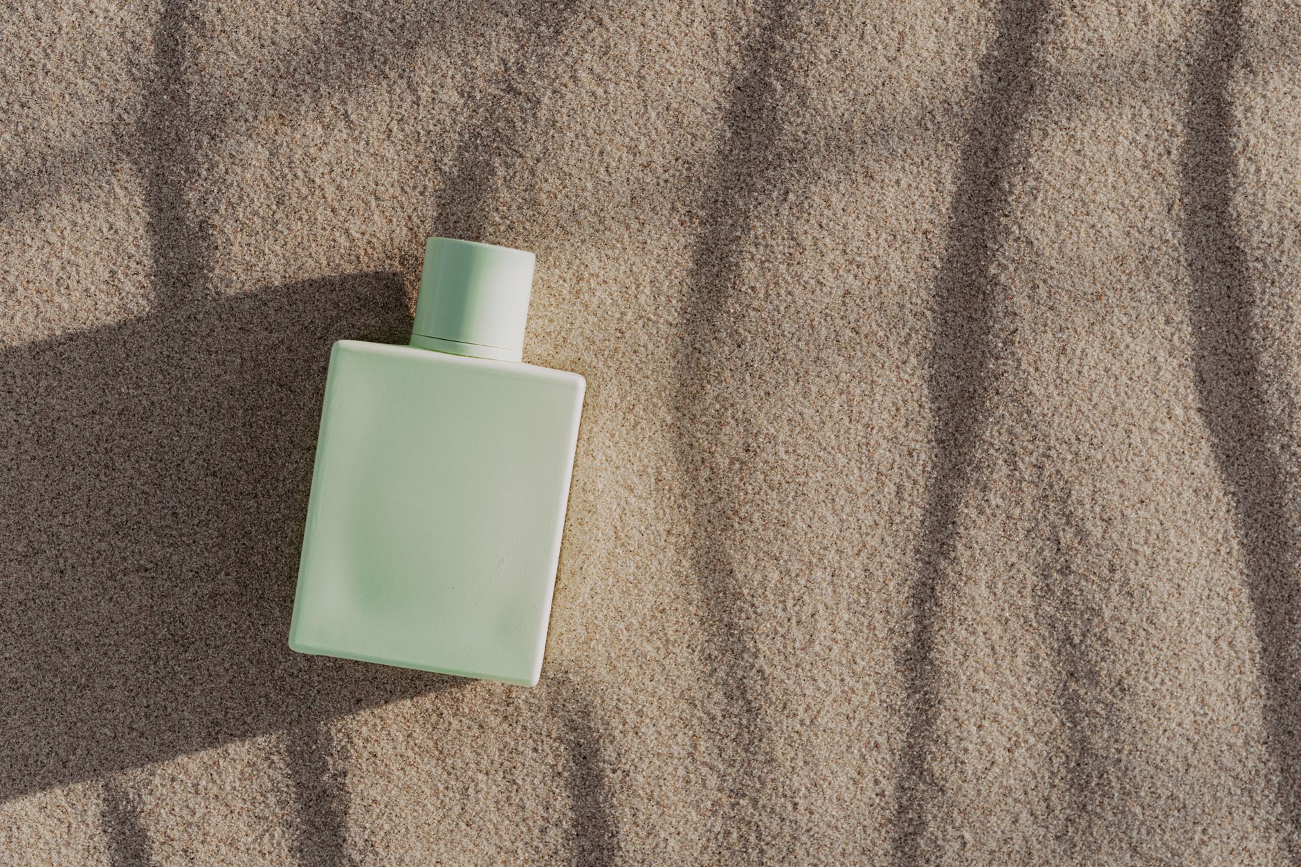 Close-up of a glass fragrance bottle on a white surface with soft natural lighting