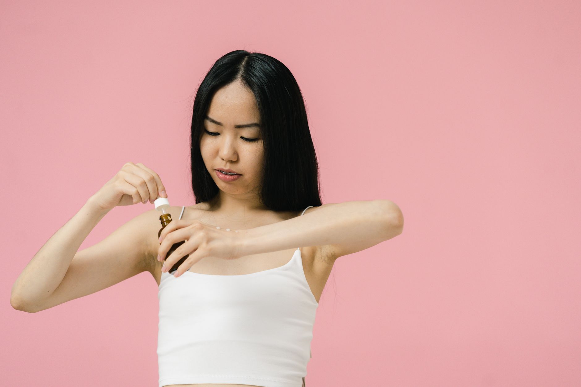 Woman applying a clear facial serum to clean skin in natural light