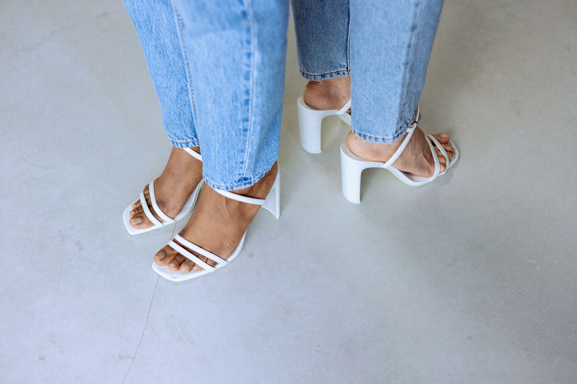 Strappy nude heeled sandals laid flat against a neutral background