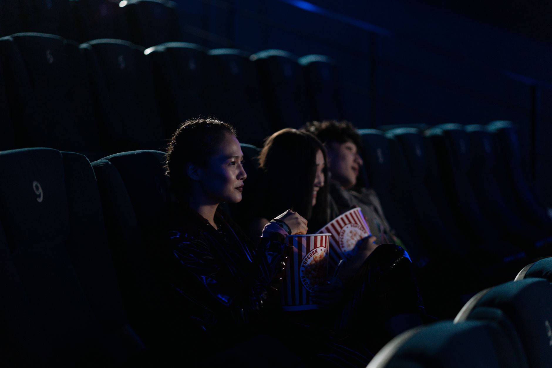 Two friends sharing an emotional moment watching a film together in a darkened theater