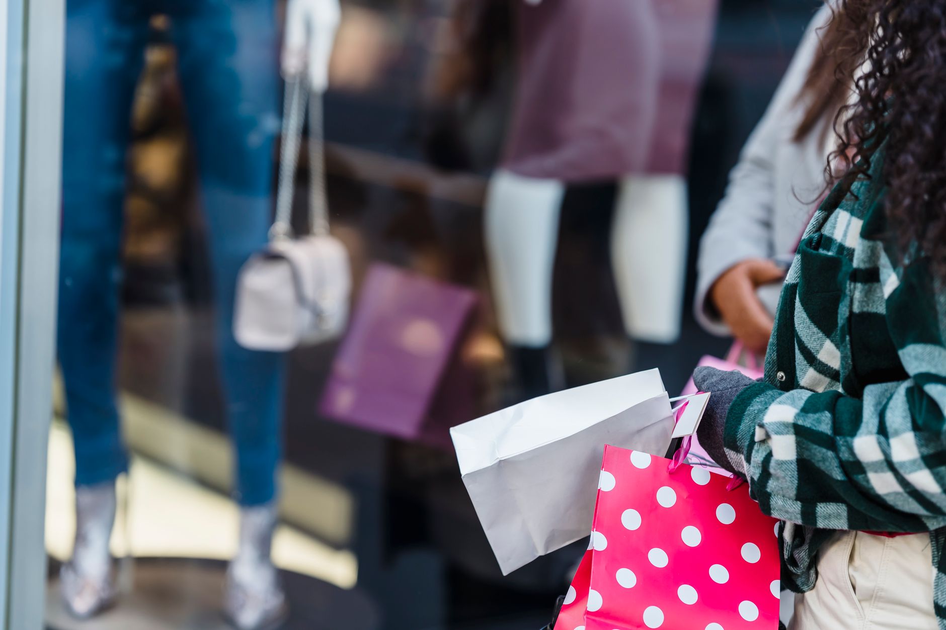 Woman carrying multiple retail shopping bags on a city sidewalk