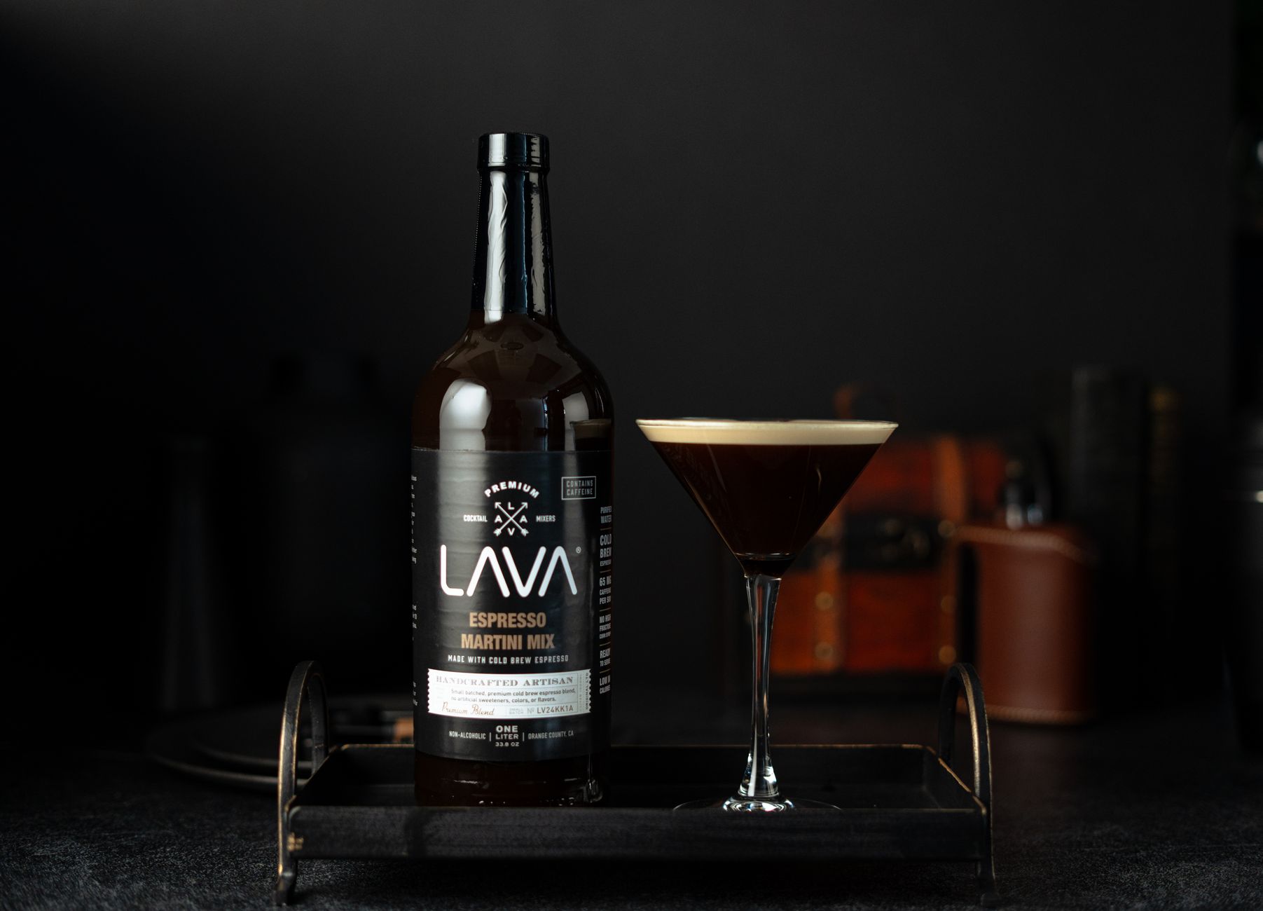 A frothy espresso martini cocktail in a coupe glass on a dark bar surface