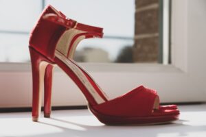 Close-up of a red-soled stiletto pump on a reflective surface