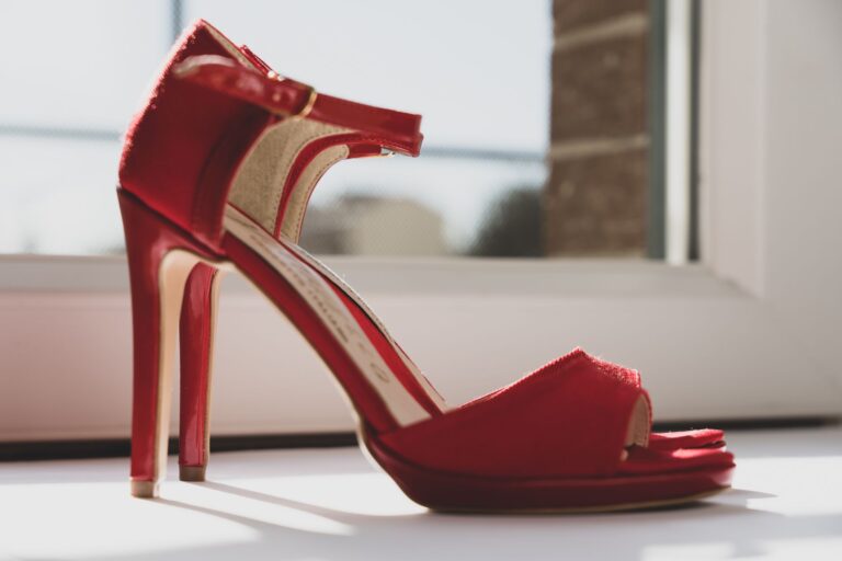Close-up of a red-soled stiletto pump on a reflective surface