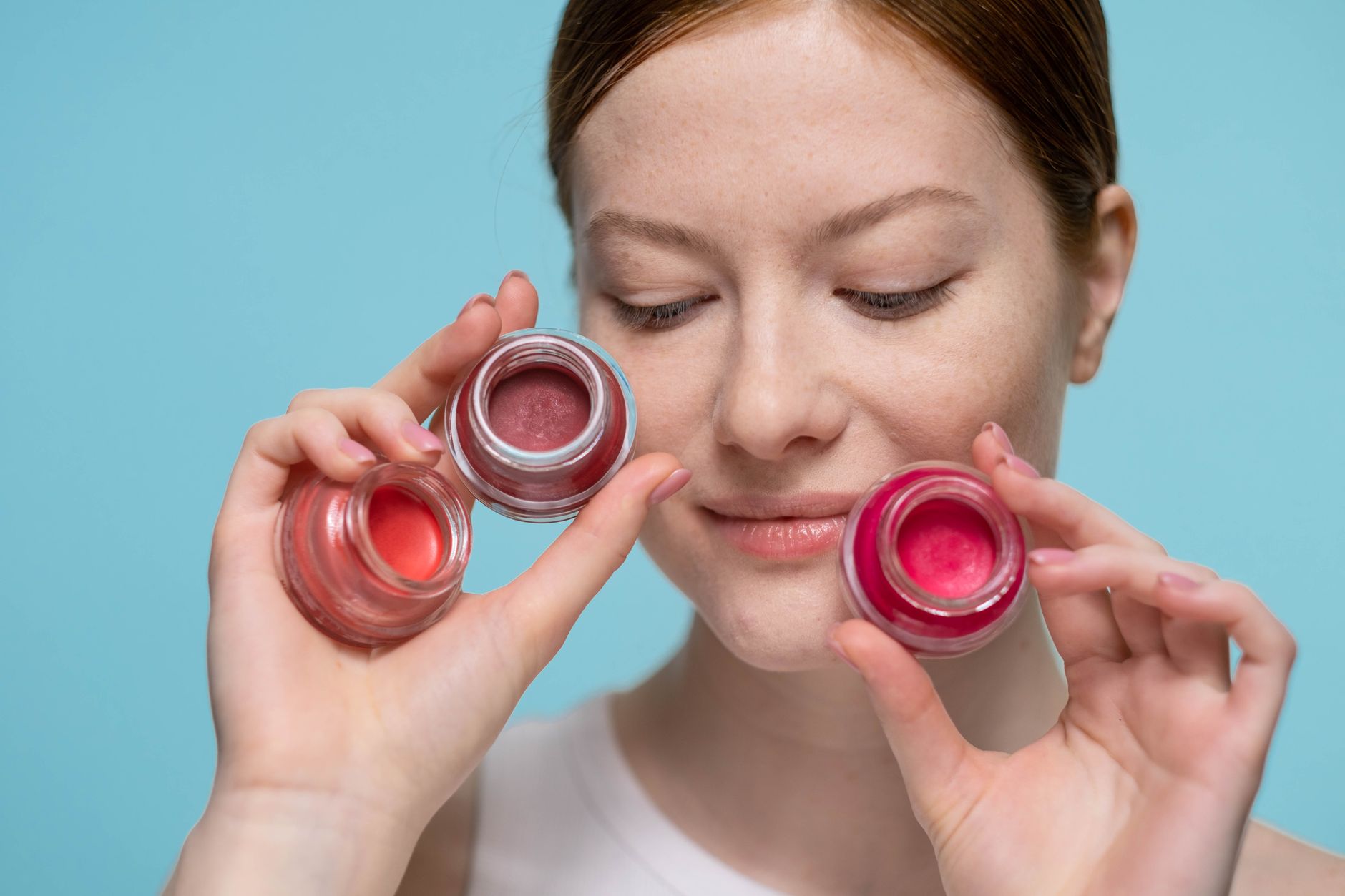 Assorted lip balm tubes and beauty products laid out flat on white background