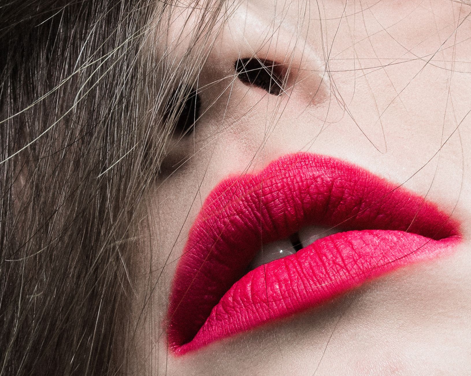 Bold red lipstick applied on a woman's face against a neutral background