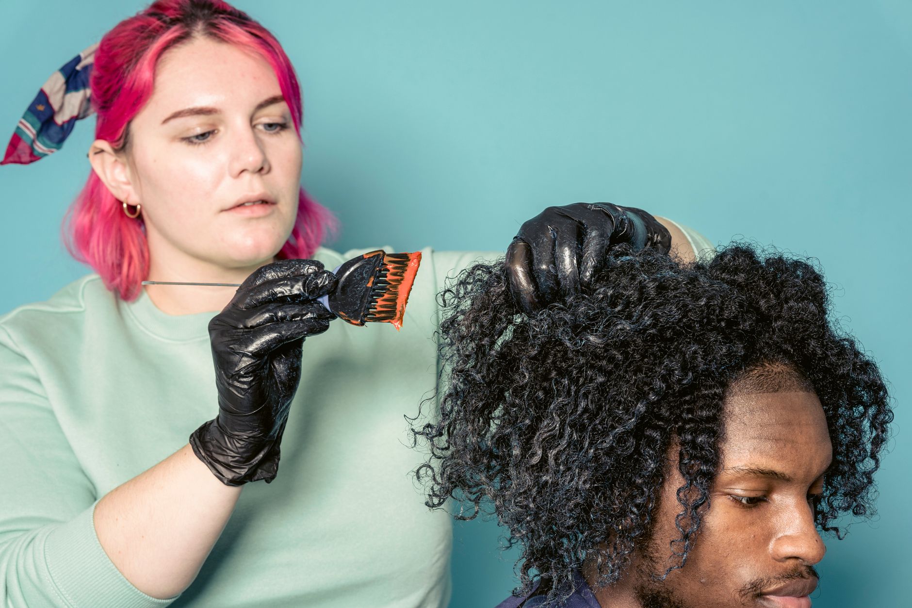 A colorist painting balayage highlights onto a client's hair with a brush