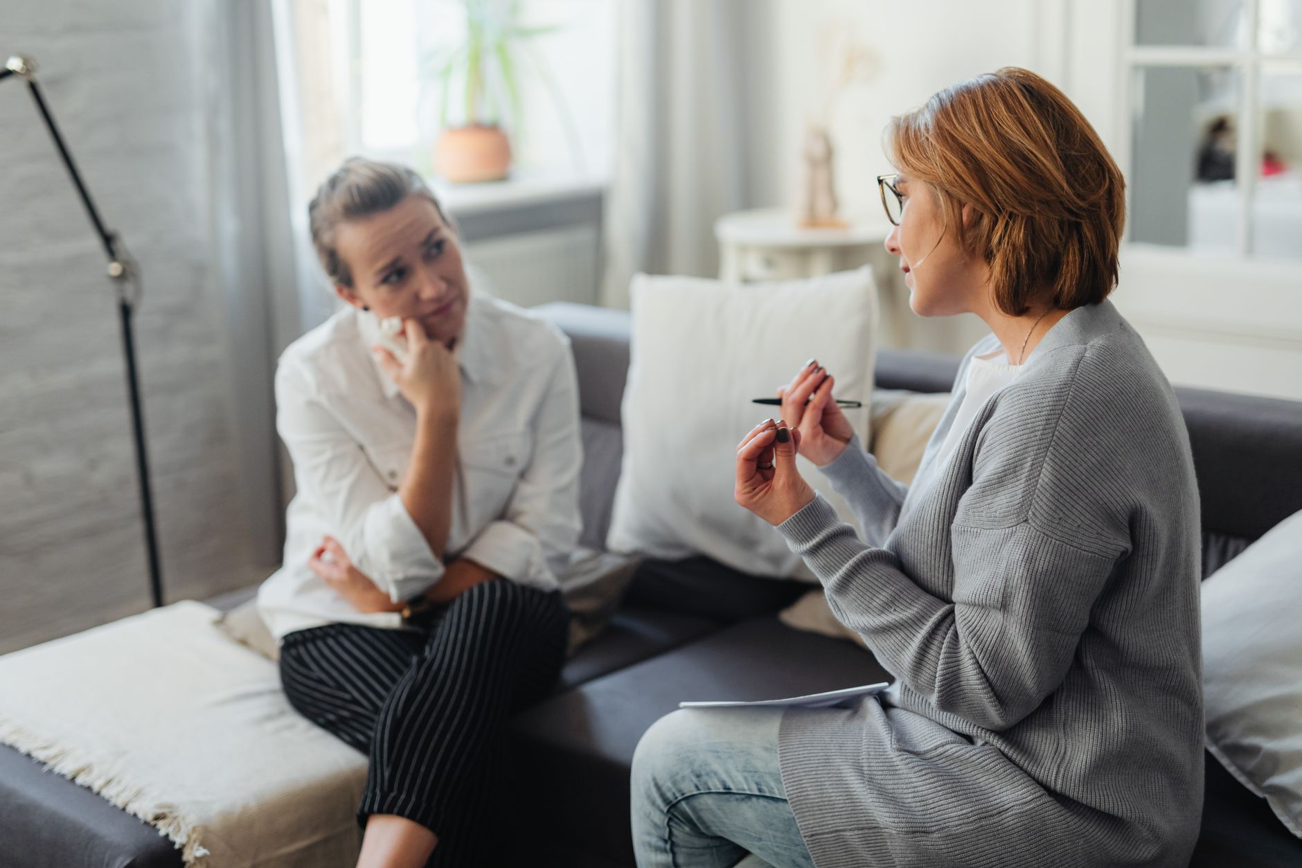 Two young women sitting together in quiet conversation, one listening attentively