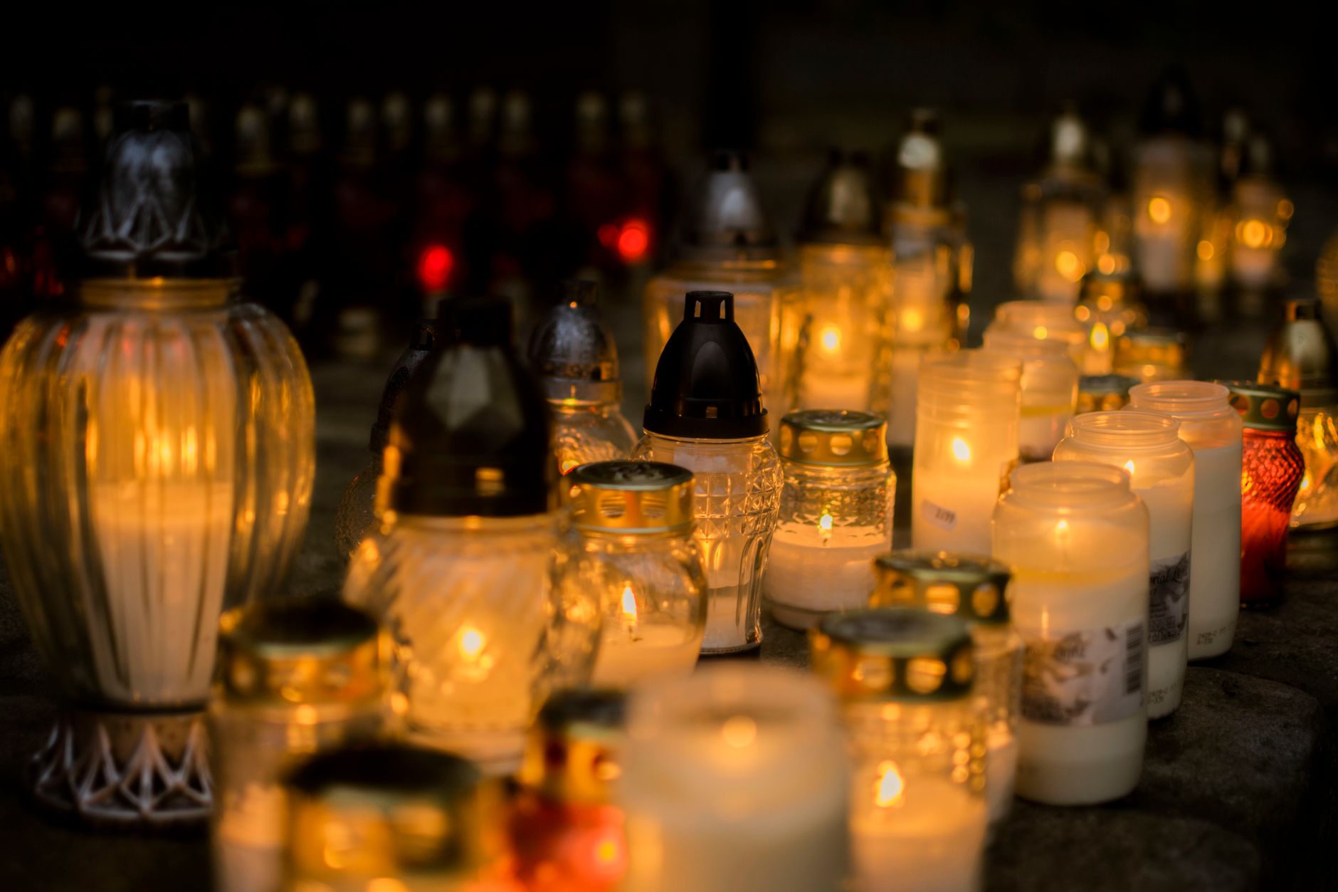 A lit candle placed near flowers as a quiet personal memorial tribute