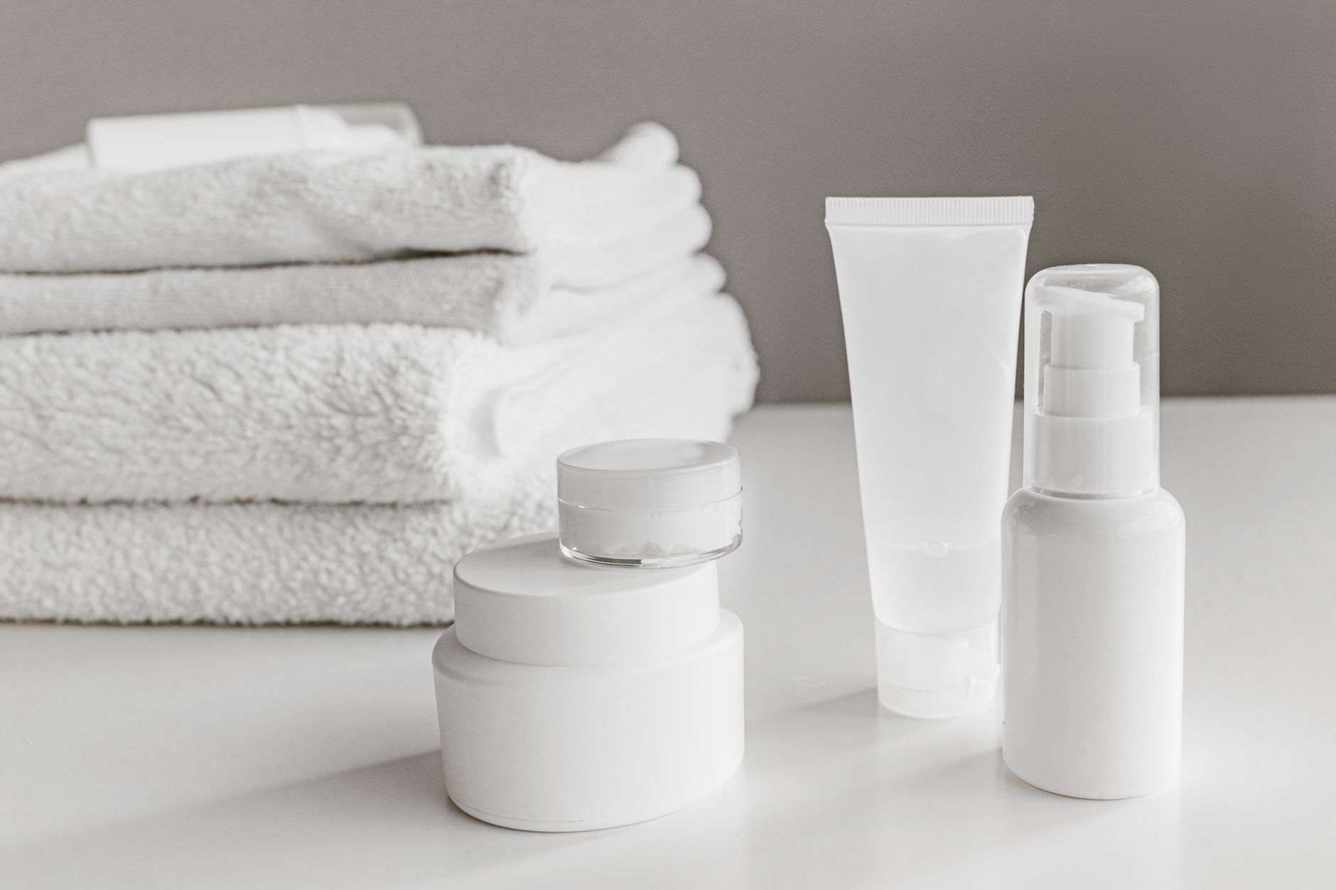 Row of high-end skincare bottles on a white surface under soft studio lighting