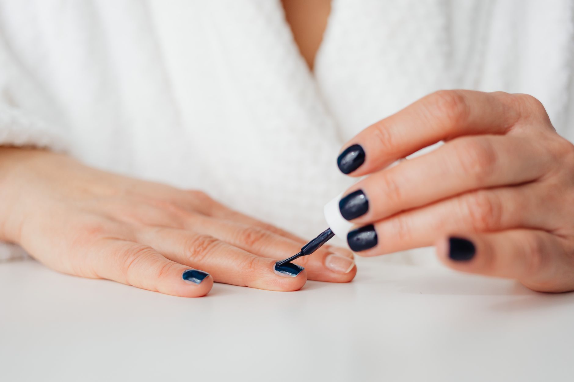 Woman carefully applying nail polish to her fingernails at home