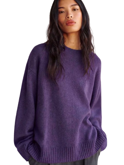 Model walking a runway in a purple ensemble during fashion week